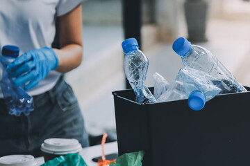 Close-up of female hands from a family collecting plastic waste and bottles from the ground. They...