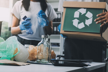 Close-up of female hands from a family collecting plastic waste and bottles from the ground. They...