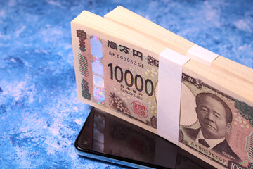 スマホと1万円札の札束