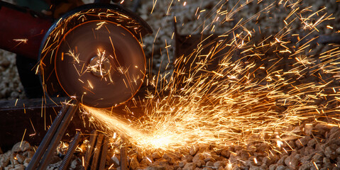 A man is using a power tool to cut through a piece of metal