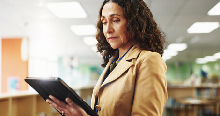 Professor, college and woman in library with tablet, education and research for knowledge. University, teacher and mature person with online app, news or technology for curriculum, school or syllabus