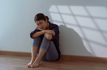 Woman sitting alone in a dimly lit room reflecting on her thoughts during the afternoon
