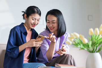 Two friends enjoying time together while using their smartphones in a cozy indoor setting during the afternoon