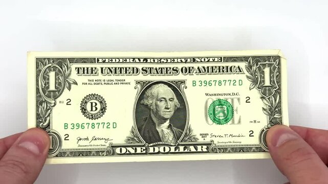Male white hands checking one bill with denomination of 1 dollar whether it is counterfeit or not on white background object in the center of the image top view