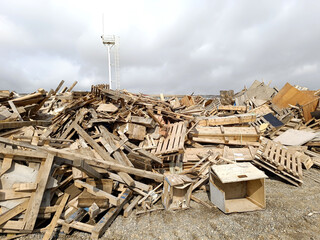 Wood waste collected for recycling outdoors in the Waste Center area. Mixed wood waste. Iron structure warehouse and mountains in the background of wood waste