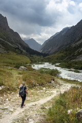 Solo female traveler trekking through the scenic mountainous landscape of Ala Archa National park...
