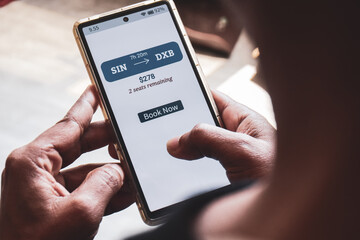 Man using mobile applications to book flight online showing one way ticket price with remaining seats available. Example of FOMO Marketing, urgency or anxiety to purchase immediately. Selective focus.