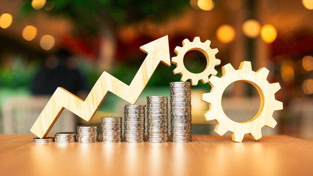 An image of a coin gradually increasing with an arrow pointing up with two wooden gears next to it. Concept of prices of goods likely to increase due to US tariffs.