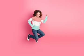 Bright and cheerful young girl jumping in casual attire against a vibrant pink background,...