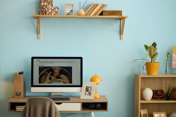 Stylish home office with wooden desk, computer, and decorative items, books, vase, and plant creating an inviting workspace in a modern room setting