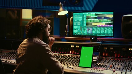 Music producer recording, mixing and reproducing sound on audio software, using stereo console and...