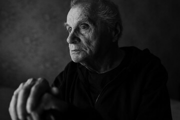Black and white portrait of an elderly man with walking stick looking directly at the camera