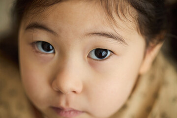 Portrait of young child staring directly into camera with intense and curious expression,...