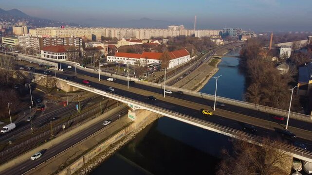 Aerial tracking of Arpad Bridge in Budapest with city roads and river beneath traffic