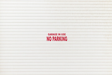 White garage door with a notice - garage in use no parking