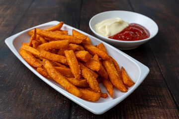 Sweet potato fries with mayonnaise on a white plate.

