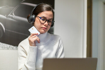 Close-up of a young woman shopping online with a laptop and a credit card.