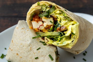 Wrap with grilled chicken, lettuce, and corn on a white plate.