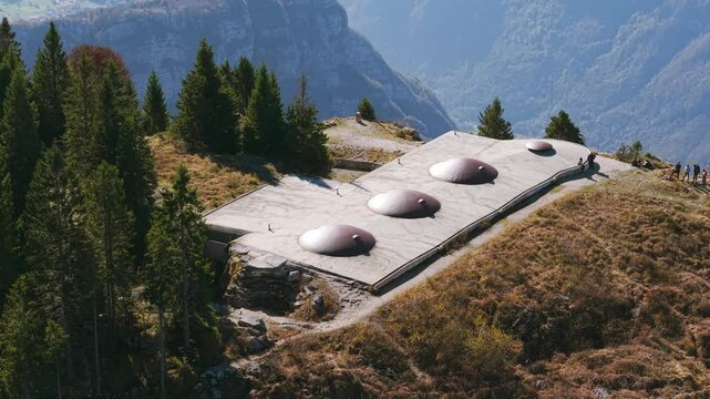 Aerial orbit of Italian Fort Campolongo on mountain with people standing outdoors