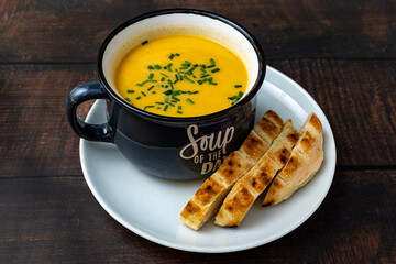 Creamy pumpkin soup with chives and toasted breadsticks.