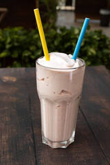 Chocolate milkshake with two straws served outdoors.