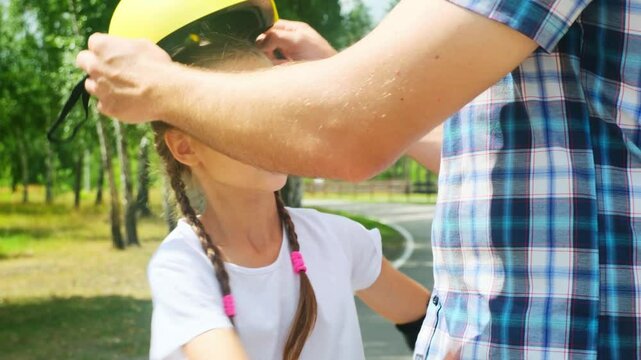 Father helped her daughter wear a yellow helmet while enjoying time together in the park