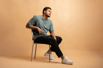 Colombian man posing sitting on chair in studio looking away