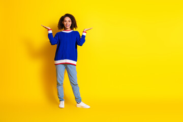 Young stylish woman in casual blue sweater posing confidently against a vibrant yellow background