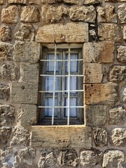 an aged window with sturdy iron grilles on an old stone house in Mardin, Turkey	