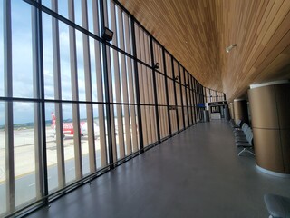 A long hallway with many windows and a plane in the background