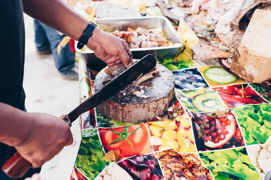 Man's hand slicing on wooden chopping board of the popular, delicious and crispy roasted pig known as "lechon baboy" (in the Philippines, Spain, Cuba, etc.). Selective focus. Copy space.