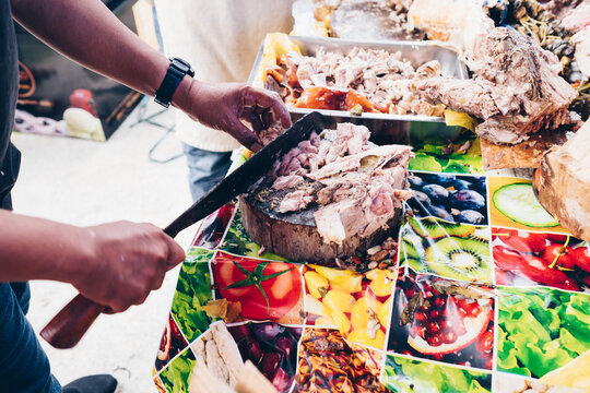Man's hand slicing on wooden chopping board of the popular, delicious and crispy roasted pig known as "lechon baboy" (in the Philippines, Spain, Cuba, etc.). Selective focus. Copy space.