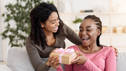 Happy birthday bestie. Black woman giving gift to her happy girlfriend at home