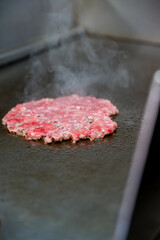 Gros plan sur un steak juteux en pleine cuisson sur une plancha professionnelle, révélant sa texture savoureuse.