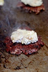Pendant la réalisation d'un hamburger; une généreuse tranche de fromage est déposée sur le steak pour qu’il fonde doucement à la chaleur.