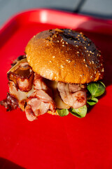 Hamburgers faits maison au fromage fondant et au bacon, disposés sur un plateau rouge.