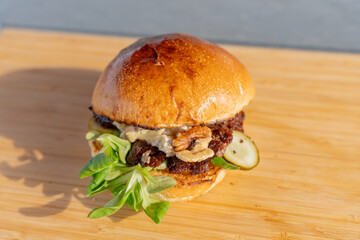 Gros plan sur un hamburger fait maison avec du fromage fondant et des noix croquantes, dans un cadre de restauration moderne.