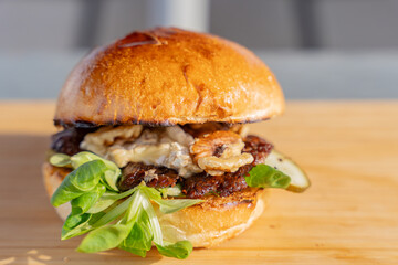 Gros plan sur un hamburger fait maison avec du fromage fondant et des noix croquantes, dans un cadre de restauration moderne.