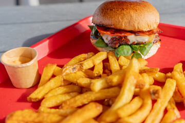 Hamburgers faits maison accompagnés de frites croustillantes, joliment présentés sur un plateau rouge dans un restaurant spécialisé.