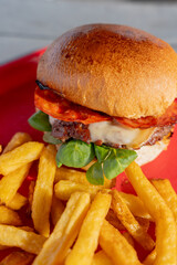 Hamburgers faits maison accompagnés de frites croustillantes, joliment présentés sur un plateau rouge dans un restaurant spécialisé.