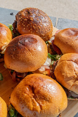 Zoom sur plusieurs hamburgers faits maison servis sur une planche en bambou dans un restaurant spécialisé.