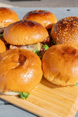 Zoom sur plusieurs hamburgers faits maison servis sur une planche en bambou dans un restaurant spécialisé.