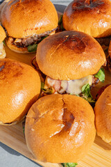 Zoom sur plusieurs hamburgers faits maison servis sur une planche en bambou dans un restaurant spécialisé.