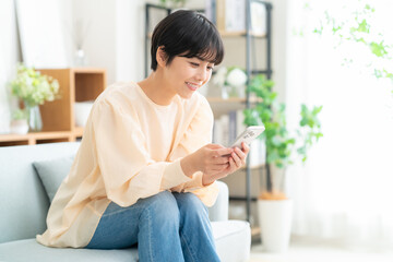 リビングでスマホを見る若い女性