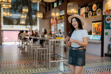 Young woman using mobile phone while ordering food in food court