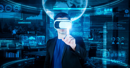 Project manager with VR goggles pointing financial chart and glowing blue light at office. Skilled...