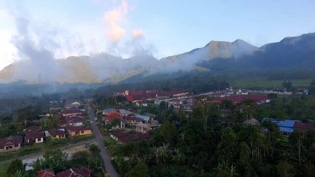 Aerial view of Ruteng town in Manggarai, East Nusa Tenggara, Indonesia, captured in the early morning light with mountain backdrop and dense residential areas.