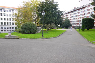 Senior woman walking in green city park surrounded by trees and buildings