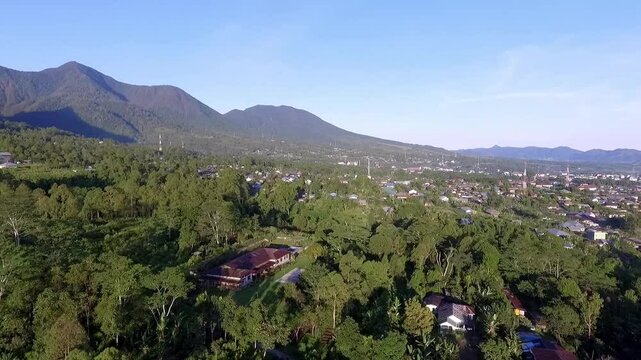 Aerial view of Ruteng town in Manggarai, East Nusa Tenggara, Indonesia, captured in the early morning light with mountain backdrop and dense residential areas.
