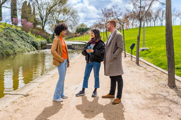 Three young professionals chatting by the canal in a park